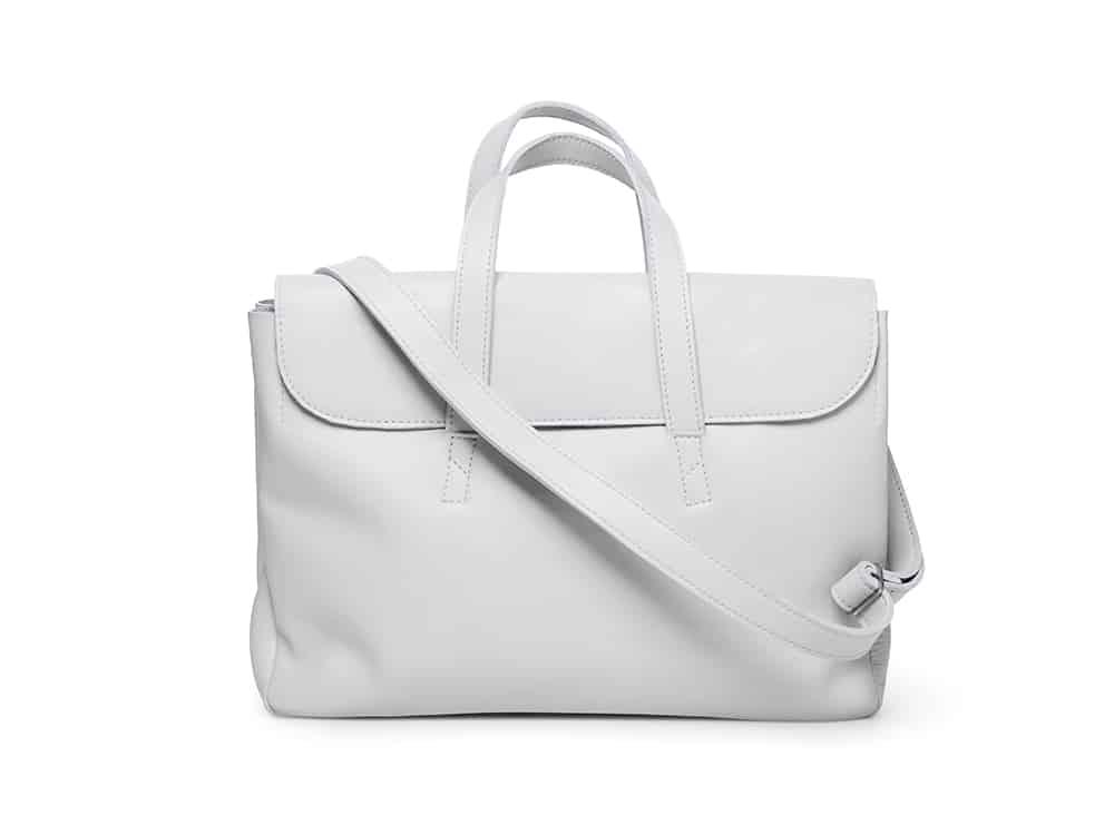 White leather handbag with top handles and adjustable shoulder strap on white background