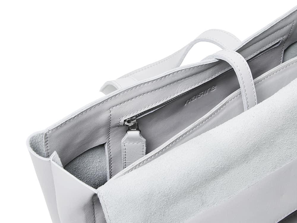 Close-up of a white handcrafted leather tote bag inner zip pocket and strap details