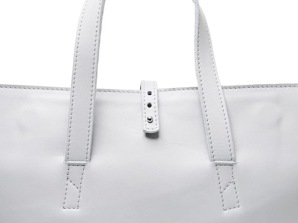 Close-up of white leather bag with stitched handles and buckle detail