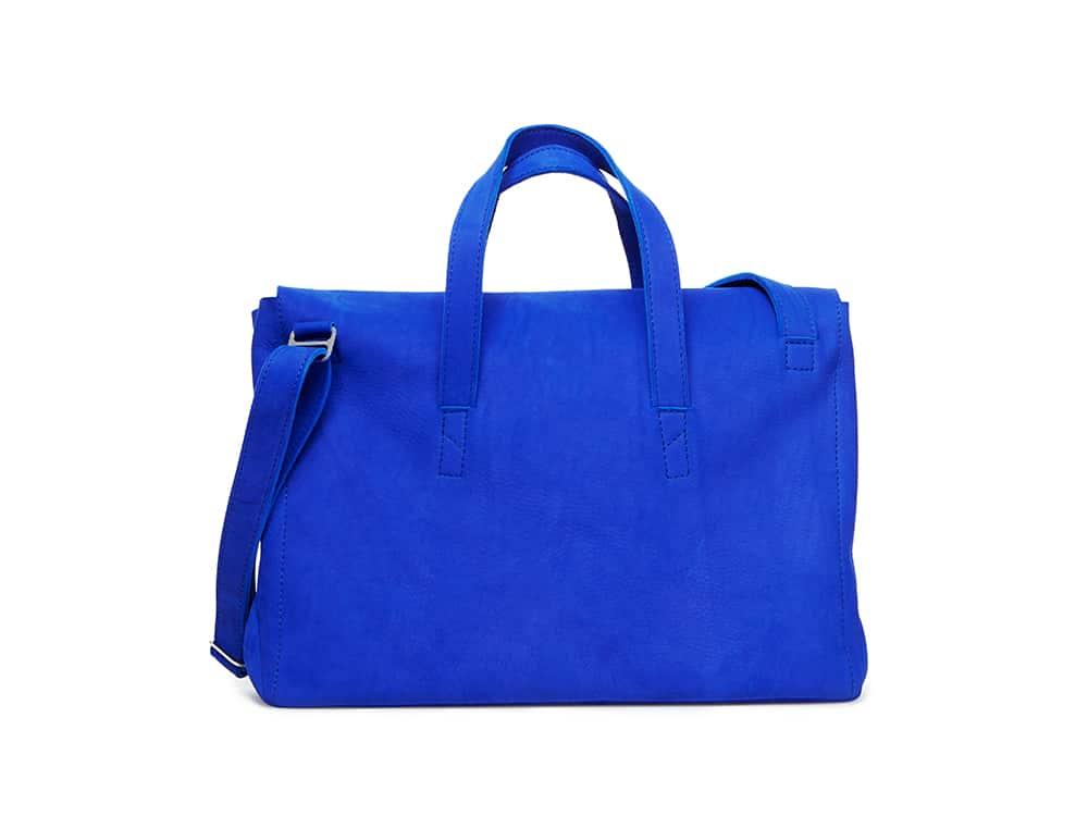Bright blue leather bag with top handles and adjustable shoulder strap on a white background