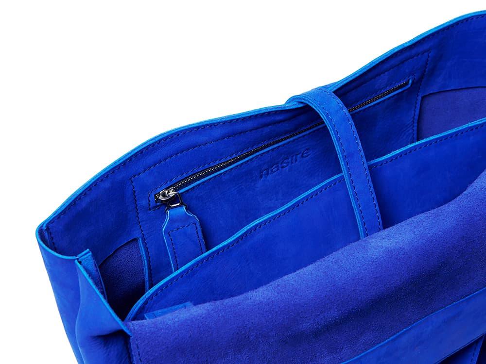 Interior view of a blue leather bag with zipper pocket and suede lining