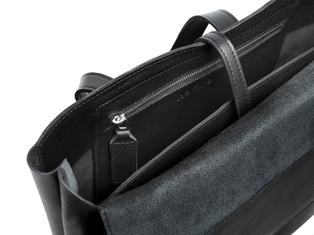 Close-up of black handcrafted leather bag with zippered interior pocket and smooth finish